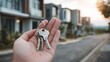 © vetrana - Holding house keys in front of new real estate development in a suburban area during late afternoon