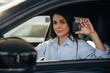 © standret - Through the window, holding keys. Woman is sitting in the modern car, happy new owner