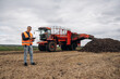 © standret - Digital tablet is in hands. Farmer is working in the agricultural field. Against beet harvester