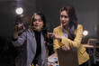 © Tj - Two young asian businesswomen are collaborating on a new business strategy, writing and discussing ideas on a clear glass wall in a modern office setup, fostering teamwork and innovation