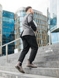© muse studio - Man walking up stairs in a modern city area during daytime
