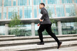 © muse studio - Man walks up stairs at modern office building carrying a laptop in the daytime