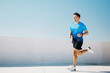 © muse studio - Man runs on a sunny day near a white wall in a sports outfit while enjoying the outdoor activity