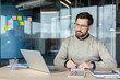 © Liubomir - Man working on laptop and writing notes in modern office