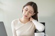 © Pormezz - Asian business woman suffering from neck pain working in office sitting at table.