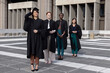 © wavebreak3 - Diverse female graduates posing on tiled plaza, adjusting mortarboard cap and showing gowns