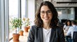 © Vasiliy - Smiling businesswoman with glasses in a bright office. Professional woman in grey blazer smiling. Modern corporate workplace and career success