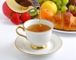 © Pemain - Tea being poured into a teacup with fruit and pastry.