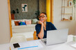 © BONNINSTUDIO/Stocksy - Woman laughing while working on laptop at home