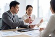 © Meow Creations - Asian businessman and businesswoman with documents and a tablet during an office meeting