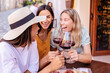 © Xavier Lorenzo - Happy women friends celebrating with red wine at outdoor cafe. Young female friends enjoying joyful social moment in Europe. Lifestyle and social concept.