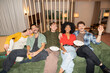 © Santi Nuñez/Stocksy - Diverse friends laughing enjoying movie night at home