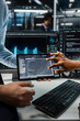 © DC Studio - Close up of system administrators using tablet in server farm with hardware supporting data mining. IT employees working together in data center to do maintenance on rigs using device