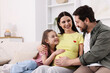 © New Africa - Pregnant woman, her husband and daughter on sofa at home. Space for text