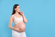 © New Africa - Choosing name for baby. Thoughtful pregnant woman on light blue background, space for text
