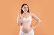 © New Africa - Choosing name for baby. Thoughtful pregnant woman on orange background