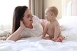 © New Africa - Mother and her cute baby on bed at home