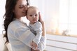 © New Africa - Smiling mother holding her cute baby at home. Space for text