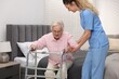 © New Africa - Care worker helping senior woman with walker to stand up from bed indoors