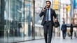 © Awais - Confident businessman walking and talking on smartphone in modern city