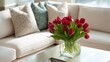 © OTaone - Elegant Living Room Setting with Fresh Red Tulips in a Glass Vase on a Modern Coffee Table Surrounded by Soft Textured Cushions