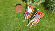 © Iuliia Sokolovska - Young girls relax in summer garden in sunbed deckchairs on grass, women friends have fun outdoors in green park on weekend, aerial drone view from above
