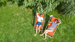 © Iuliia Sokolovska - Young girls relax in summer garden in sunbed deckchairs on grass, women friends have fun outdoors in green park on weekend, aerial drone view from above