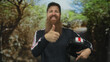 © Krakenimages.com - Man with long beard holds helmet and shows thumbs up in green forest clearing to highlight head protection and outdoor adventure; confidence.