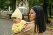 © phpetrunina14 - Mother Holding Baby in Yellow Outfit at Park early autumn