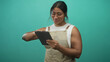 © Krakenimages.com - Woman in apron tapping a tablet with fingers, smiling and holding the device against a teal studio backdrop; calm concentration.