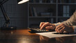 © Vyatcheslav - Businessman working late at night in office with calculator and lamp. Overtime financial analysis and budget planning concept
