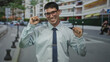 © Krakenimages.com - Young hispanic man with clenched fists and broad smile on sunlit city street with parked cars; celebration joy confidence.