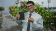© Krakenimages.com - Young hispanic man in shirt and tie smiling and pointing finger to notebook on street near plants; optimism.