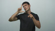 © Krakenimages.com - Young hispanic man in black tee shirt holds l hand shape and points finger in light gray studio; focus confidence.