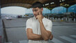 © Krakenimages.com - Young hispanic man with folded arms in white t shirt at airport terminal entrance outdoors; reflection.