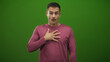 © Krakenimages.com - Man with right hand on chest and pursed lips in studio with green backdrop, glance sideways and hesitant posture suggesting self doubt and surprise; vulnerability surprise.