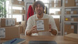© Krakenimages.com - Man holds cardboard package at building desk, hands reaching forward offering parcel; determination entrepreneurial business.