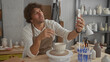 © Krakenimages.com - Man paints a glazed ceramic cup on a pottery wheel while holding a phone to record and using a small brush in an artist studio; concentration.