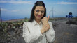 © Krakenimages.com - Young woman holding wrist in outdoor park with wind turbines and clear sky in background, expressing discomfort or pain
