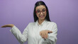 © Krakenimages.com - Young hispanic woman scientist in a lab coat with glasses presenting something with an excited expression against a purple wall.