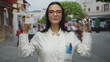 © Krakenimages.com - Woman optician wearing glasses and uniform holds credit card and eyewear in a bustling outdoor street setting.