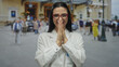 © Krakenimages.com - Young hispanic woman scientist smiling in a white uniform on a busy street with blurred pedestrians and historic buildings in the backdrop, exuding confidence and joy.