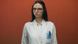 © Krakenimages.com - Woman in white uniform with red glasses gesturing no with finger in front of red wall expressing disapproval and focus in scientific setting