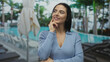 © Krakenimages.com - Woman pondering at a sunny hotel resort by the pool, surrounded by palm trees, exuding relaxation and vacation vibes while enjoying an outdoor leisure experience.