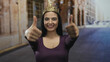 © Krakenimages.com - Hispanic woman wearing a crown gives thumbs up while smiling on a sunny street, capturing joy and confidence in an outdoor urban setting.