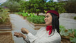 © Krakenimages.com - Hispanic flight attendant in uniform gestures outdoors in a park with vibrant greenery, embodying cheerful professionalism and cultural diversity under a sunny sky.
