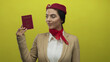 © Krakenimages.com - Woman flight attendant in uniform holding turkish passport against yellow wall with confident expression suggesting travel authority