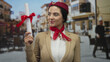 © Krakenimages.com - Hispanic woman flight attendant celebrating graduation with diploma on a lively street setting outdoors, embodying success and achievement.