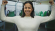 © Krakenimages.com - Confident young hispanic woman smiling and flexing muscles inside a bus showcasing strength travel empowerment and positivity in a public transportation setting