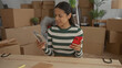 © Krakenimages.com - Young woman counts money in new home surrounded by boxes holding a phone and enjoying her new apartment environment